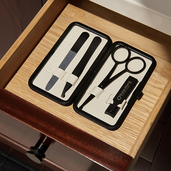 The Blue and White Air-Safe Manicure Set with Teflon instruments lies open in a wooden cabinet draw