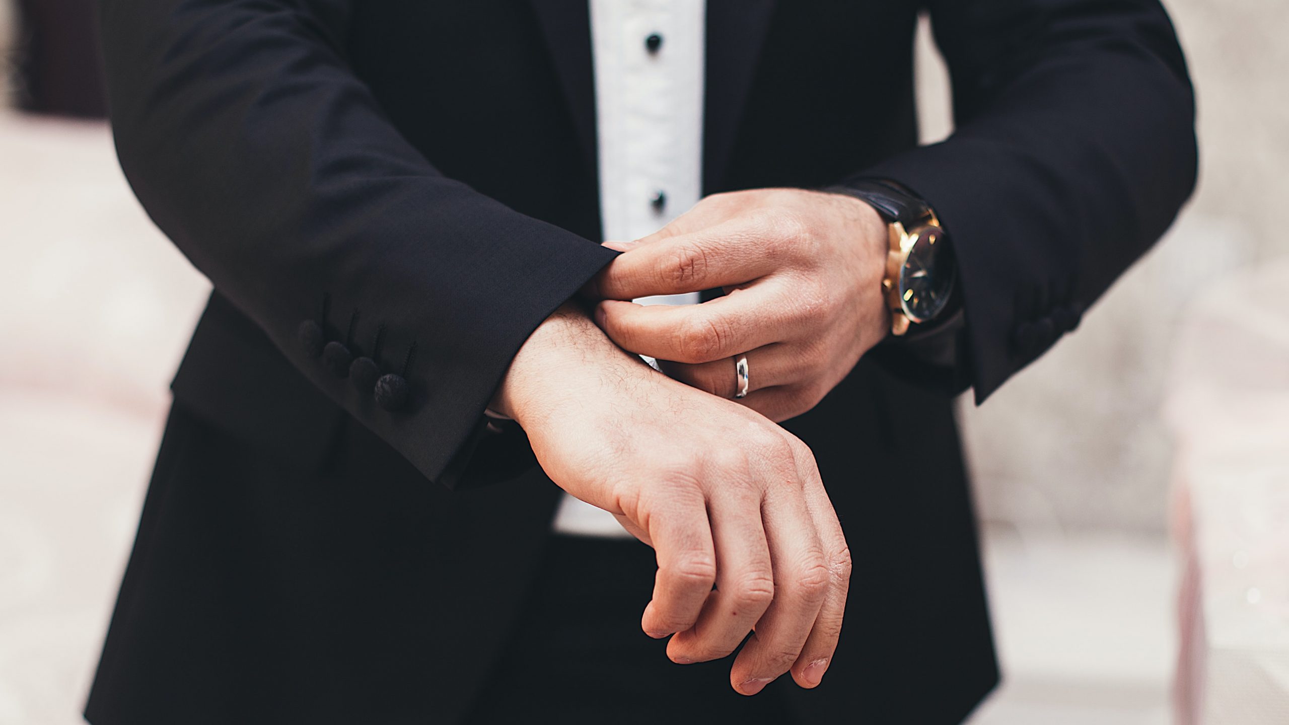 Close up of man wearing black tie suit ring and watch
