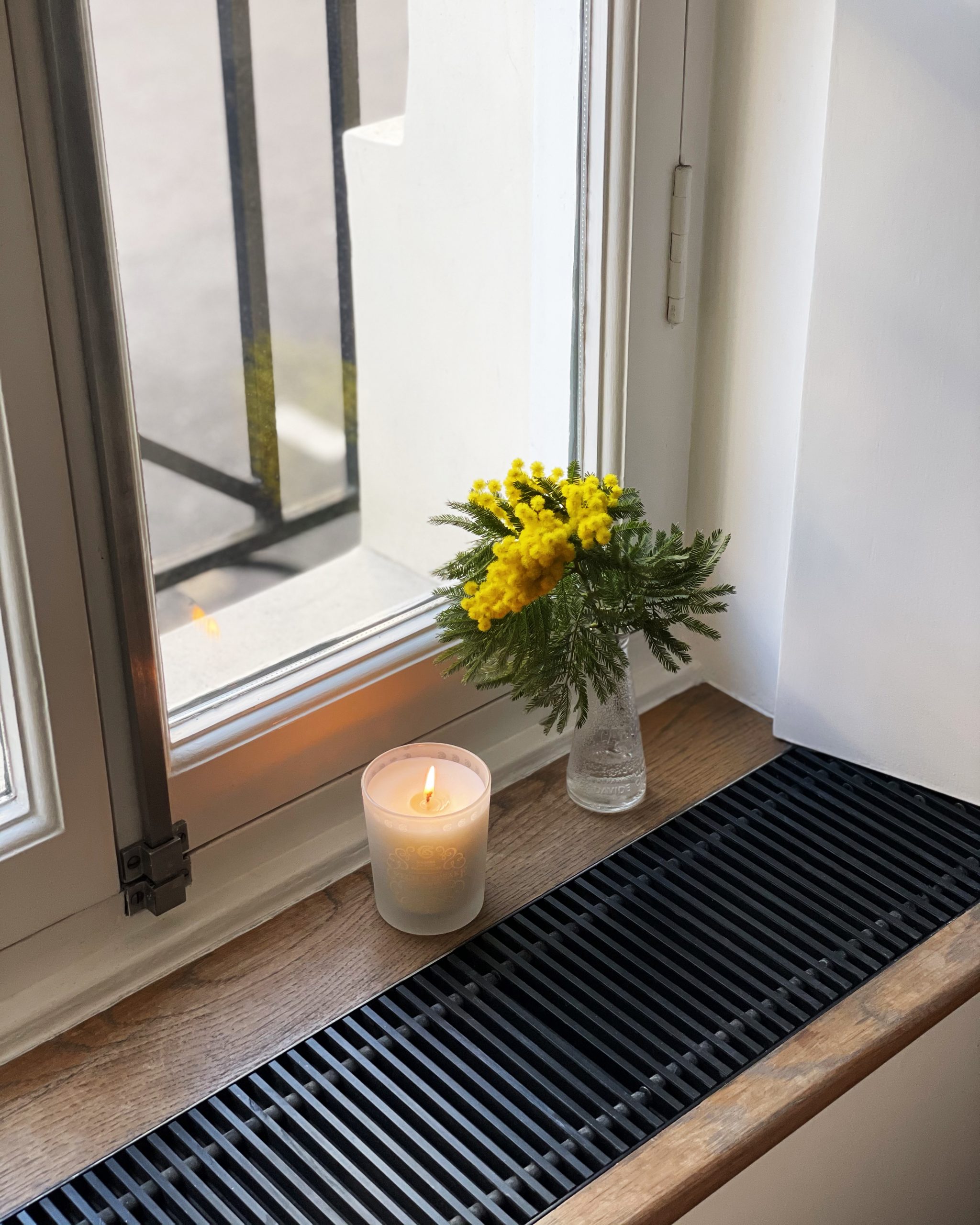 Scented candle with mimosa flowers window sill