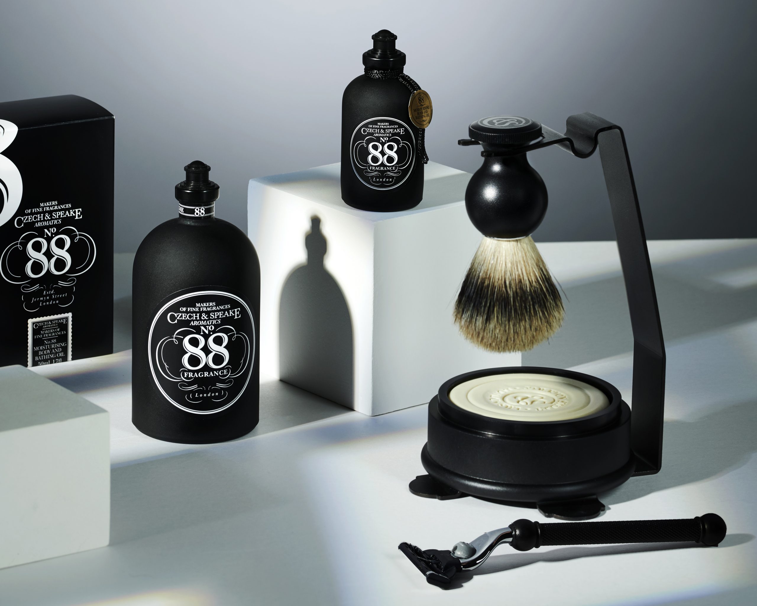 Minimal scene with white blocks and the No.88 collection. No.88 Cologne 200ml, No.88 Moisturising Bath & Body Oil and the No.88 Shaving Set & Stand.