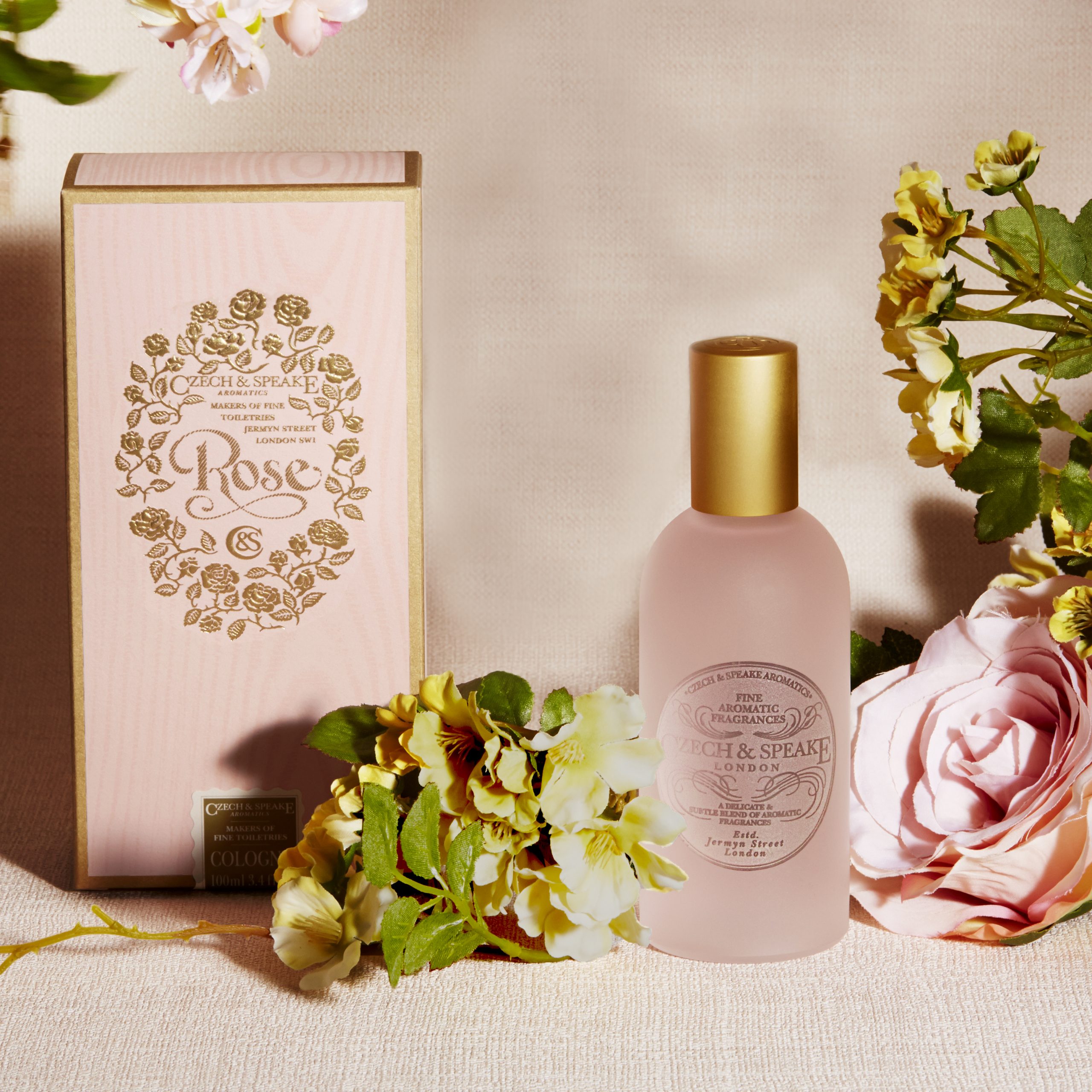 Rose Cologne bottle and packaging on pink linen background with roses