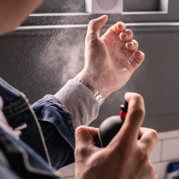 men spraying fragrance on wrist
